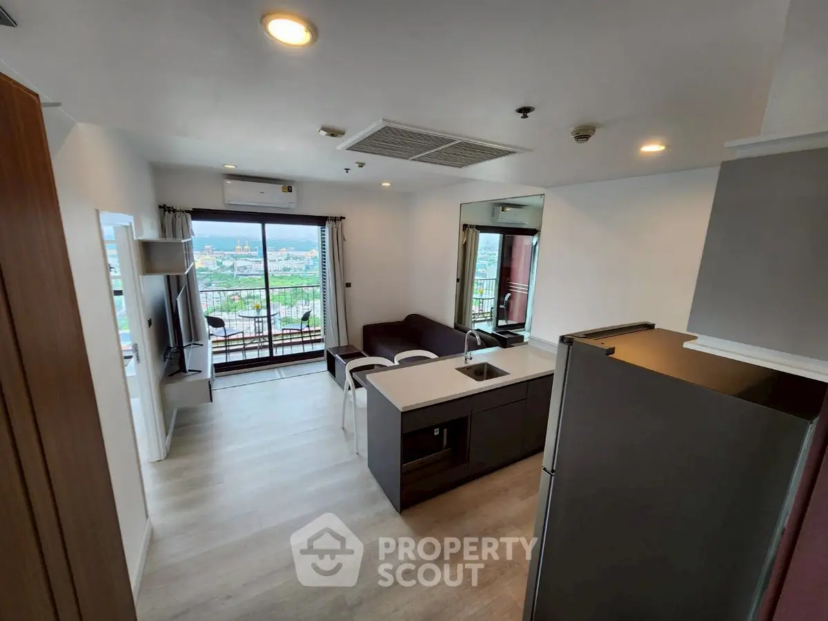 Modern open-plan living room with kitchen and stunning city view from balcony.