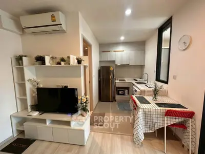 Modern open-plan living room with kitchen, featuring sleek decor and natural light.