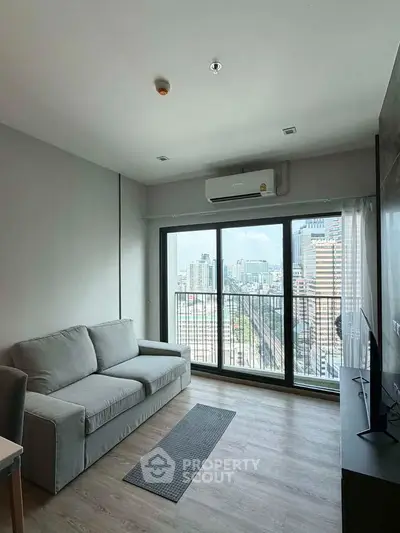 Modern living room with city view and large windows in a high-rise apartment.
