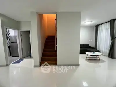 Modern living room with staircase and sleek design, featuring a cozy seating area and stylish decor.