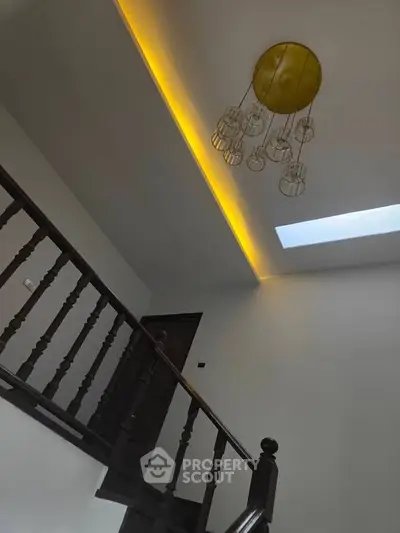 Elegant staircase with modern lighting and skylight in a stylish home interior.