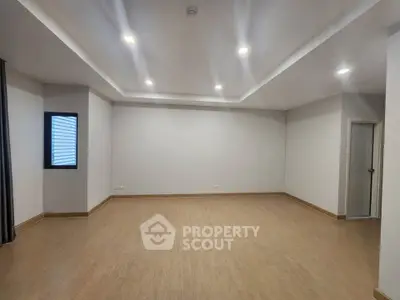 Spacious empty room with modern lighting and wooden flooring, ideal for customization.