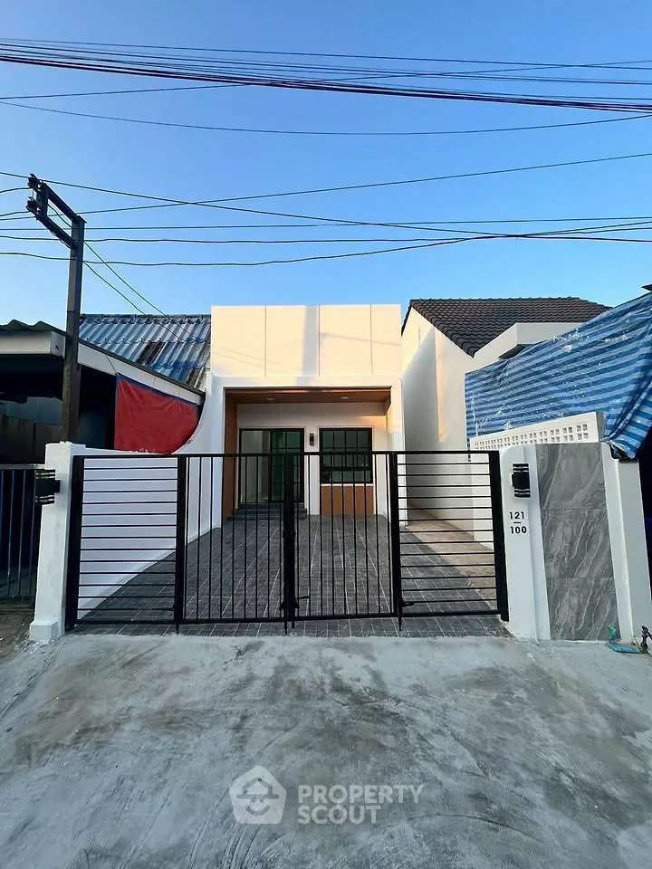 Modern single-story house with gated entrance and sleek design in a suburban neighborhood.
