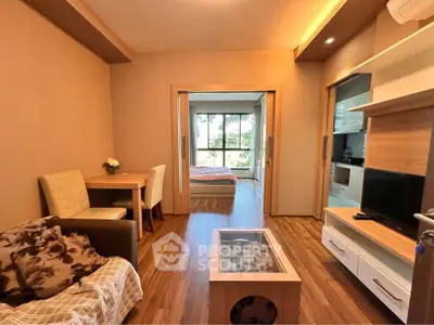 Modern living room with wooden flooring and cozy decor leading to a bright bedroom.