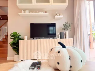 Chic living room with modern decor and cozy ambiance, featuring a stylish TV setup and plush accents.