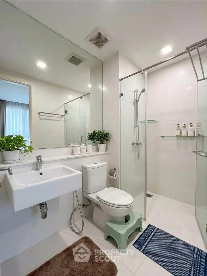 Modern bathroom with glass shower, sleek fixtures, and elegant decor.