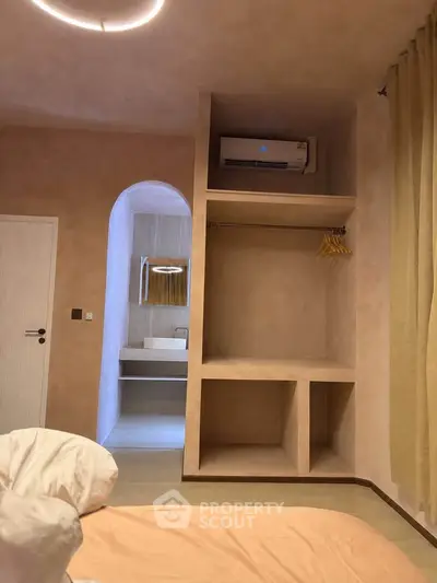Modern bedroom with built-in closet and view into stylish bathroom