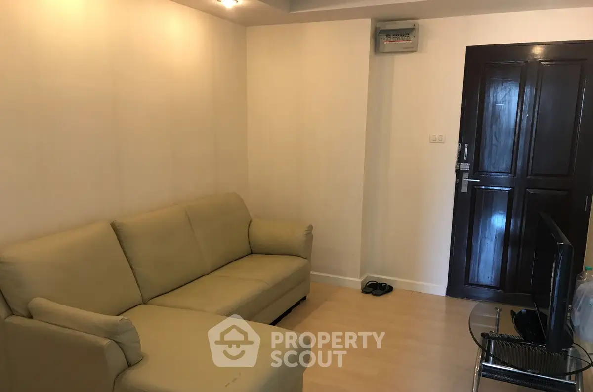 Cozy living room with beige sofa and wooden door, perfect for relaxation.