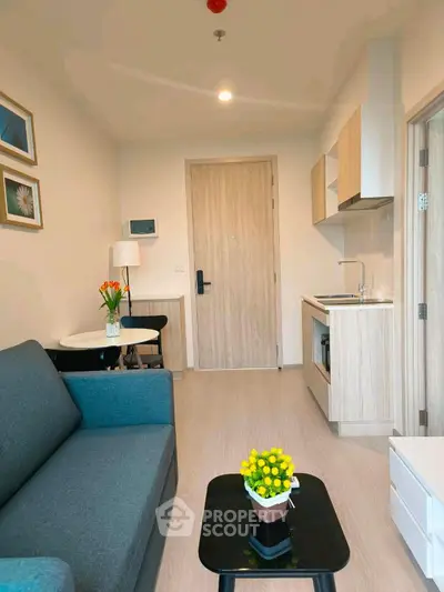 Modern compact living room with kitchenette, stylish decor, and cozy seating area.
