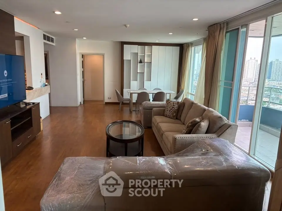 Spacious living room with modern furniture and city view balcony in luxury apartment.