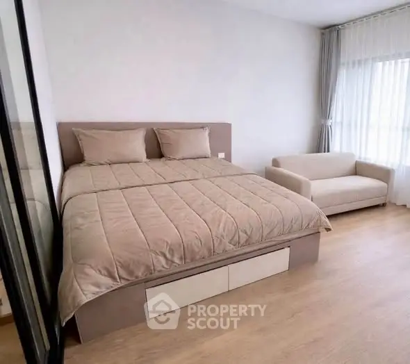 Spacious bedroom with modern decor and natural light, featuring a cozy bed and elegant sofa.