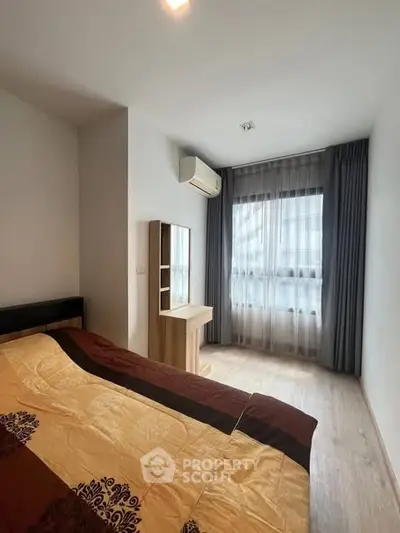 Cozy bedroom with modern decor and large window for natural light.