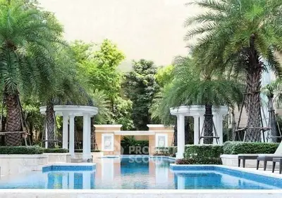 Luxurious outdoor pool area with elegant columns and lush palm trees in a serene garden setting.