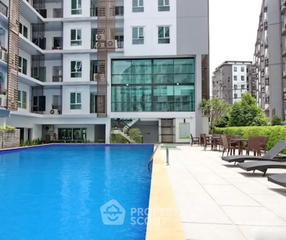 Modern apartment complex with pool and outdoor seating area.