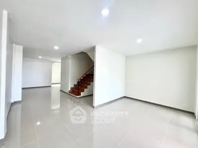 Spacious modern living area with sleek staircase and glossy tile flooring.