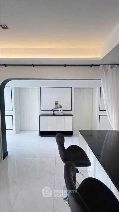 Modern minimalist living room with sleek black and white decor and stylish bar stools.