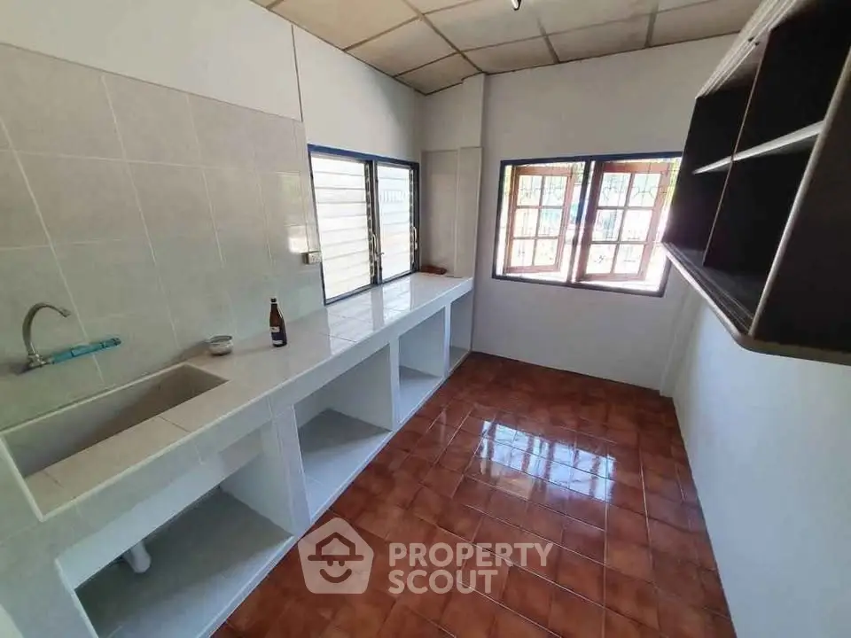 Spacious kitchen with tiled flooring and ample counter space in a bright, airy setting.