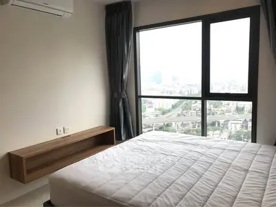 Modern bedroom with large window offering stunning city view and minimalist decor.
