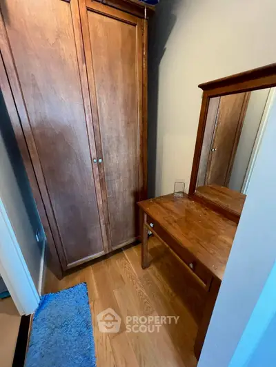 Cozy bedroom corner with wooden wardrobe and dressing table, perfect for compact living spaces.