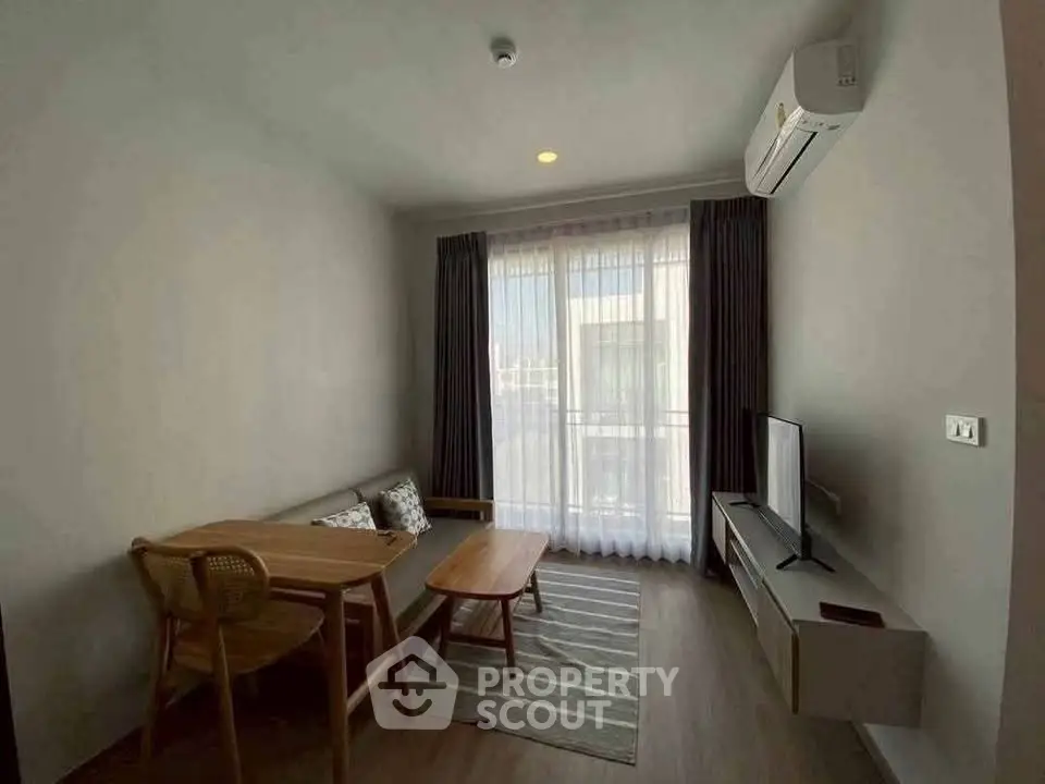 Modern living room with natural light, featuring a cozy sofa, dining table, and wall-mounted TV.