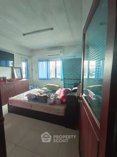 Cozy bedroom with natural light and tiled flooring, featuring a comfortable bed and ample storage space.