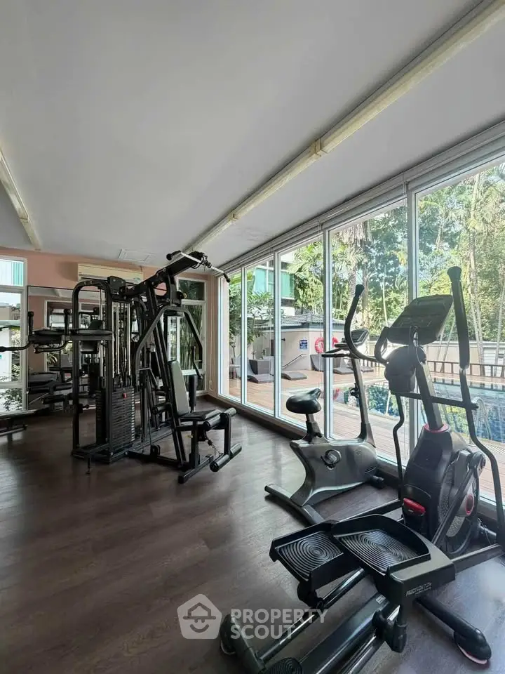 Modern gym with state-of-the-art equipment and large windows overlooking lush greenery.