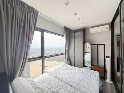 Stunning bedroom with panoramic city view, featuring modern decor and large windows for natural light.