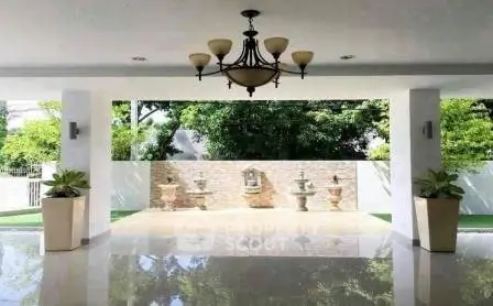 Spacious covered outdoor area with elegant chandelier and garden view