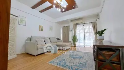 Spacious living room with modern decor and natural light, featuring a cozy sofa and elegant wooden accents.