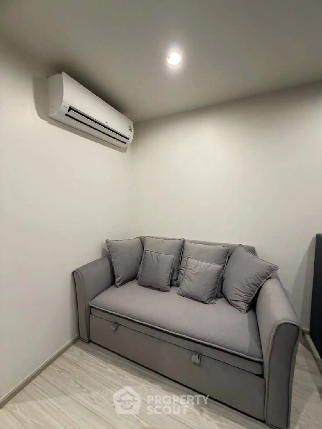 Cozy small living room with gray sofa and air conditioning unit, perfect for relaxation.