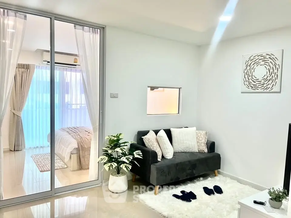 Modern living room with cozy decor and glass partition to bedroom