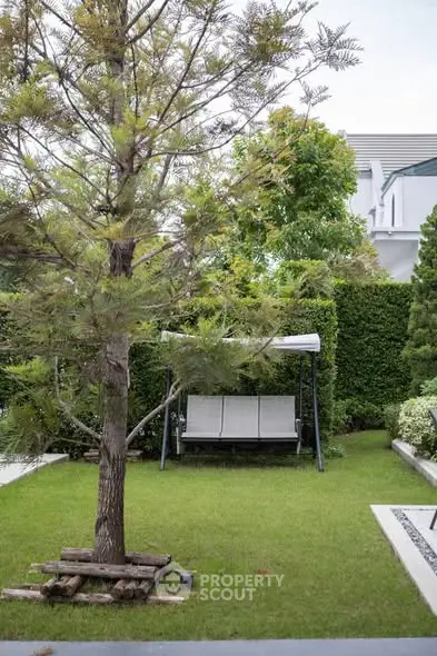 Charming garden with a swing bench and lush greenery, perfect for relaxation and outdoor enjoyment.