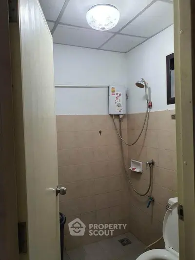 Compact bathroom with shower and toilet in a minimalist design.