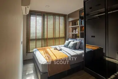 Modern bedroom with stylish decor and natural light through wooden blinds.