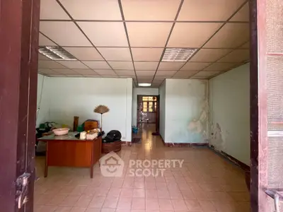 Spacious interior room with tiled floor and ceiling lights, ideal for office or storage use.