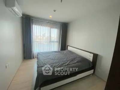 Spacious bedroom with large window and modern furnishings in a bright apartment.