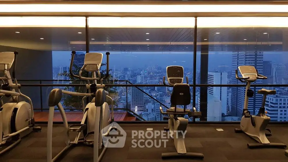 Modern gym with city view and exercise equipment in high-rise building.