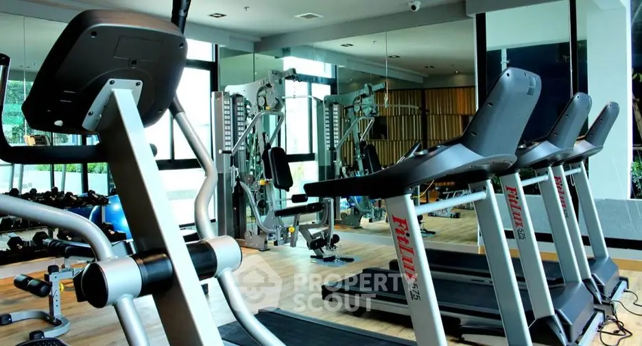 Modern gym with state-of-the-art fitness equipment and mirrored walls in luxury real estate property.