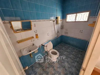 Spacious bathroom with blue tiles and modern fixtures, featuring a window for natural light.