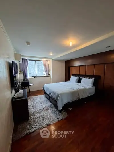 Spacious bedroom with wooden flooring and city view window, featuring a cozy bed and modern decor.