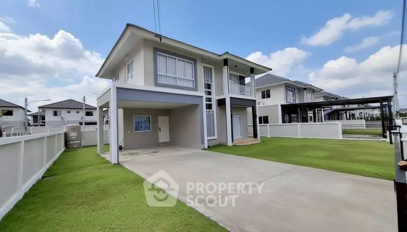 Modern two-story house with spacious driveway and lush green lawn under clear blue sky.