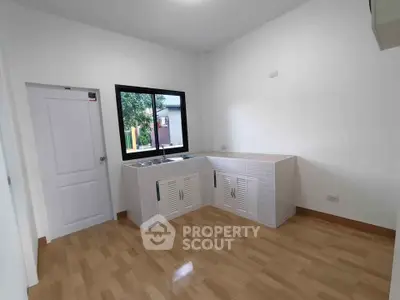 Modern kitchen with wooden flooring and large window for natural light