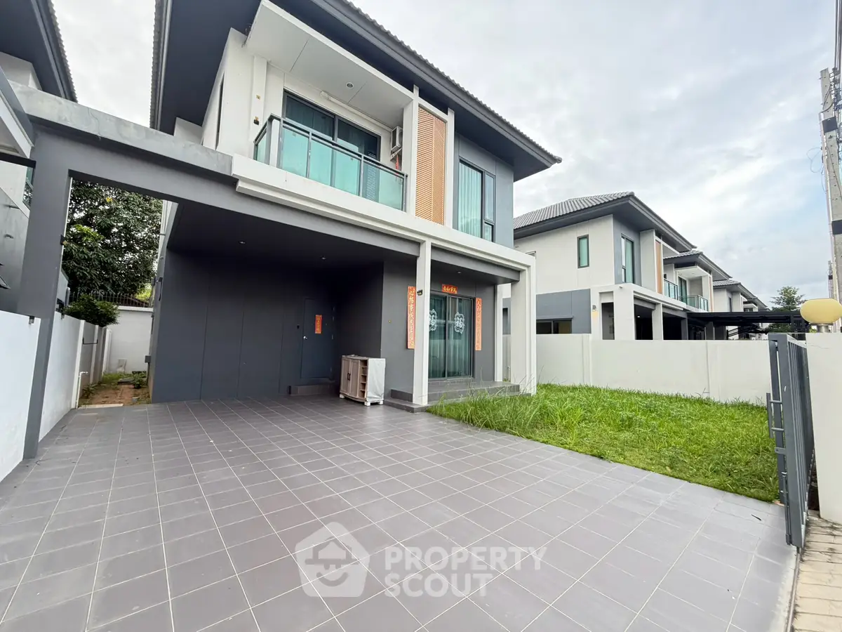 Modern two-story house with spacious driveway and green lawn in a serene neighborhood.
