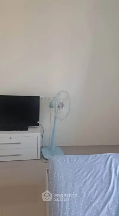 Cozy bedroom with TV and fan, perfect for relaxation.