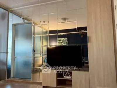 Modern living room with mirrored wall and sleek TV stand, showcasing contemporary design and spacious layout.