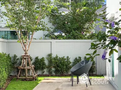 Charming garden patio with modern chair and lush greenery, perfect for relaxation and outdoor enjoyment.