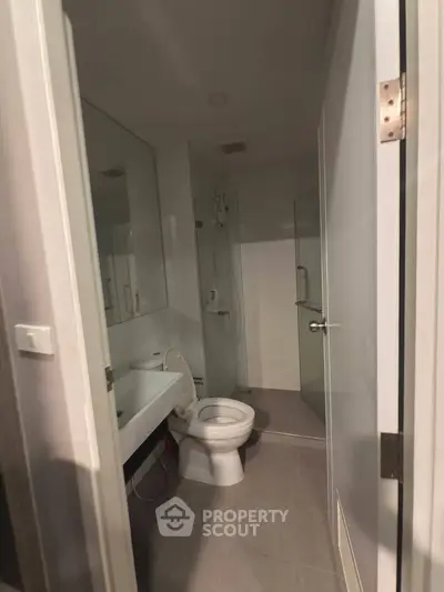 Modern bathroom with sleek fixtures and glass shower enclosure in a contemporary apartment.