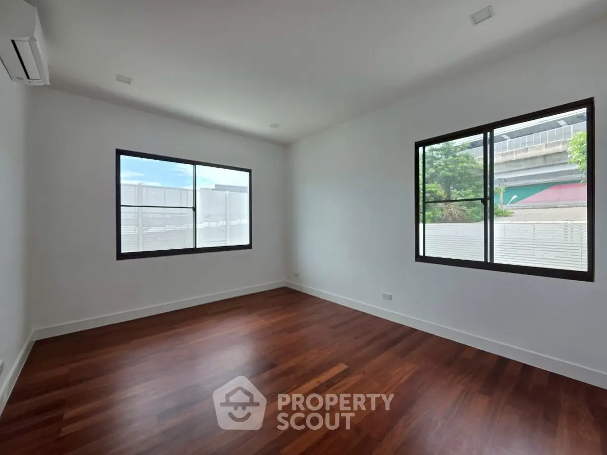 Spacious empty room with wooden floors and large windows, ideal for customization.