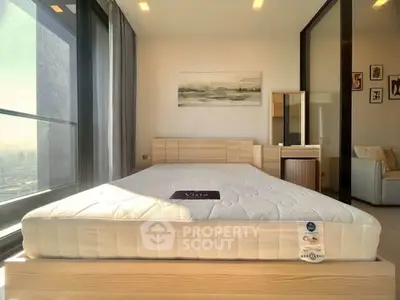 Spacious bedroom with large windows and modern furnishings in a high-rise apartment.
