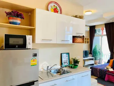 Charming kitchen with modern appliances and cozy living area in open layout apartment.